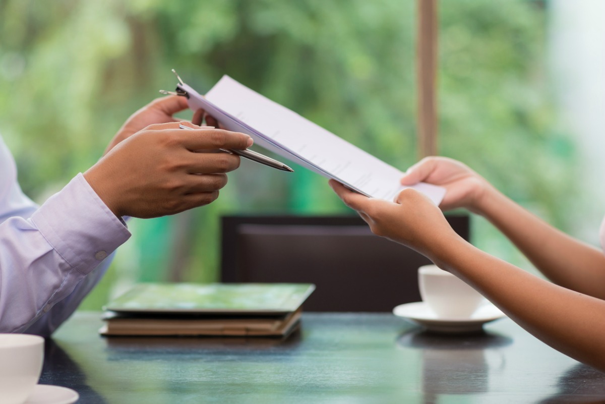 Hand of businessman giving document to his female colleague